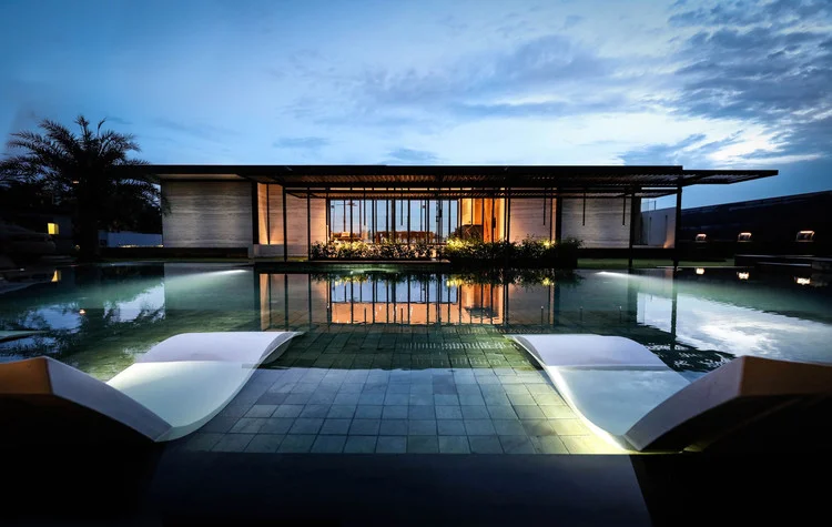 A contemporary villa reflected in a pool at dusk