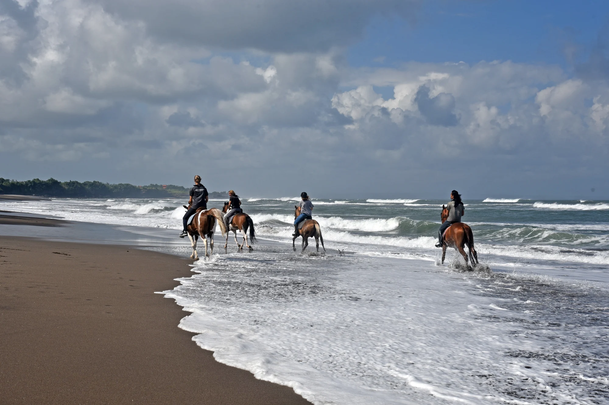 Riders on the dark-sand beach at Kedungu, Bali