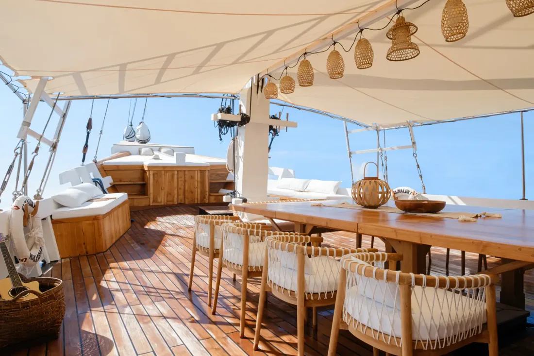 A shaded private dining table on a yacht deck with sea views